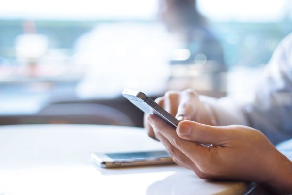 Businessman using mobile payments in office background