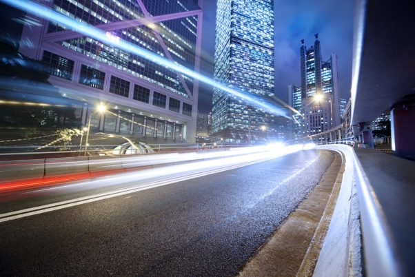 Fast moving cars lights blurred over modern city background