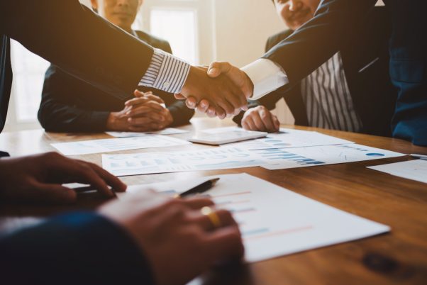 Young man business people shaking hands after brief job for contract signing in modern office with vintage picture style, colleagues at meeting teamwork of partnership.