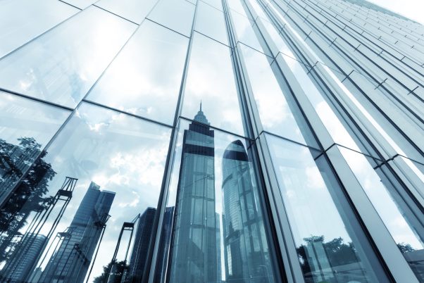 a skyscraper with glass walls and the reflection of landmarks on the opposite side